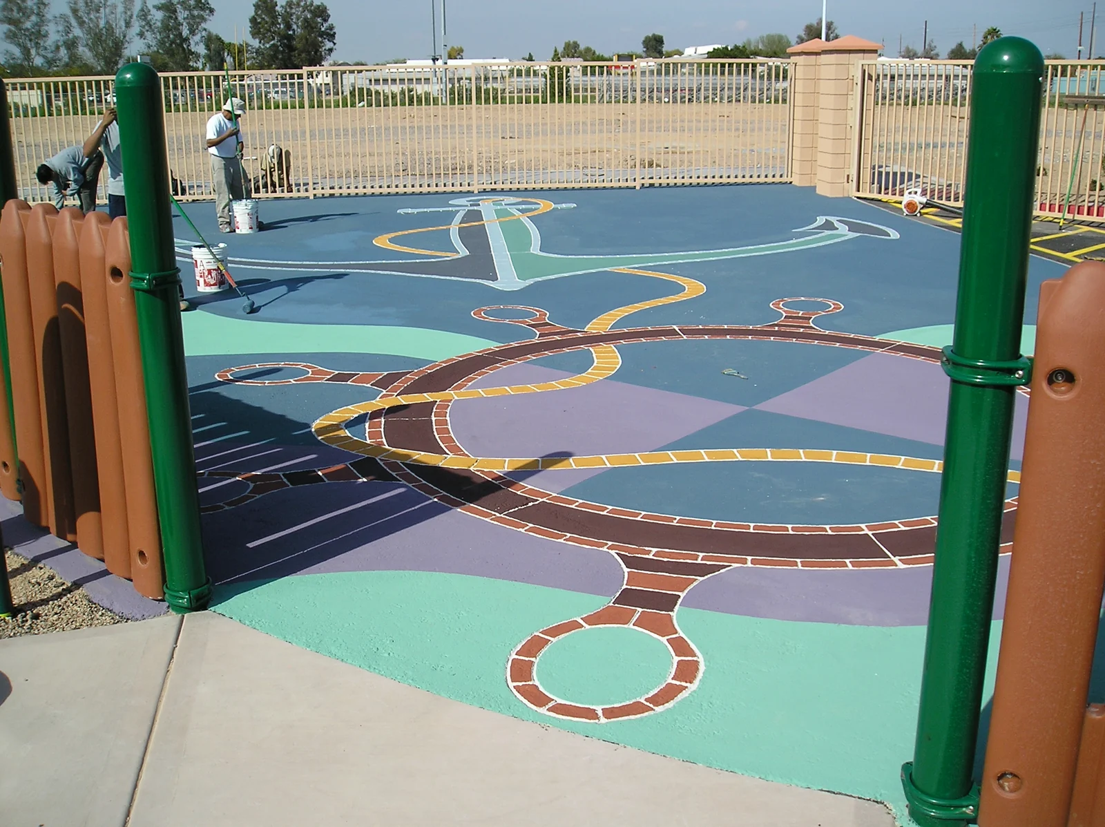 Colorful decorative asphalt playground design during installation, with workers applying the surface